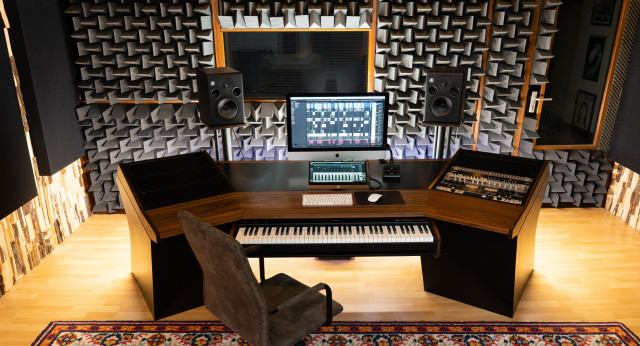 Muziek studiodesk, met keyboard, randapparatuur, speakers en een iMac.